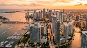 Vista aérea de Brickell Miami con rascacielos modernos y Biscayne Bay al atardecer.